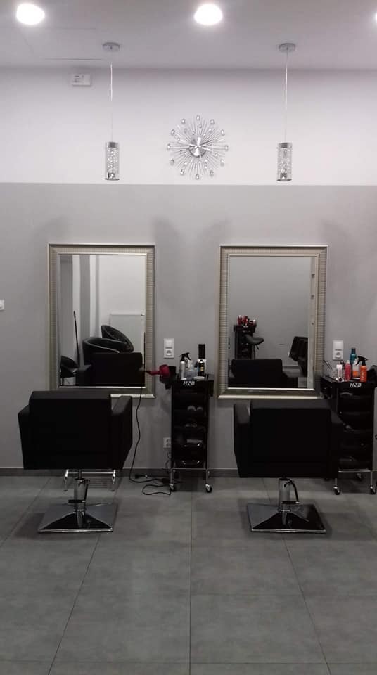 Wnętrze salonu z czarnymi fotelami i lustrami w srebrnych ramach